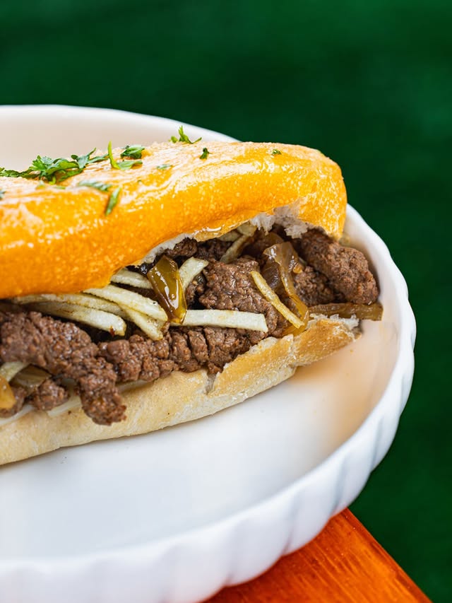 Sándwich de carne y cebolla servido en un plato blanco